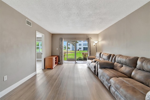 living room with light wood-type flooring and a textured ceiling