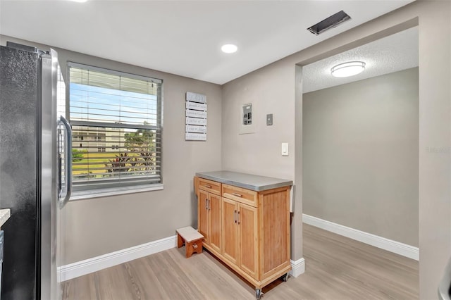 kitchen featuring light hardwood / wood-style floors, a textured ceiling, and stainless steel fridge