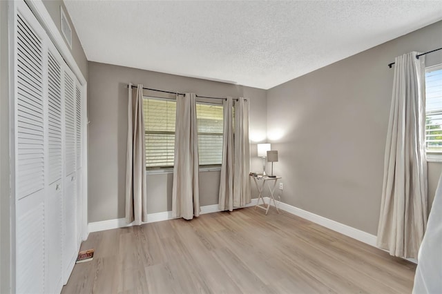 unfurnished bedroom with light hardwood / wood-style floors, a closet, and a textured ceiling