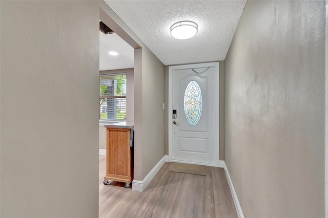 entryway with light hardwood / wood-style floors and a textured ceiling