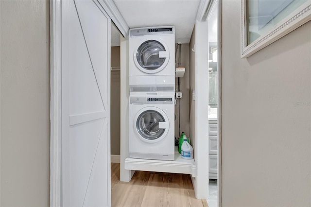 laundry room with hardwood / wood-style flooring and stacked washer and clothes dryer