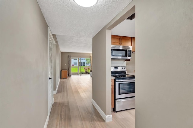 hall with light hardwood / wood-style flooring and a textured ceiling