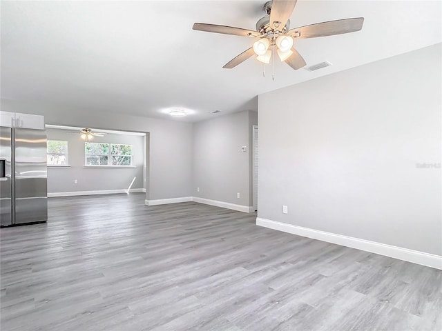 empty room with ceiling fan and light hardwood / wood-style flooring