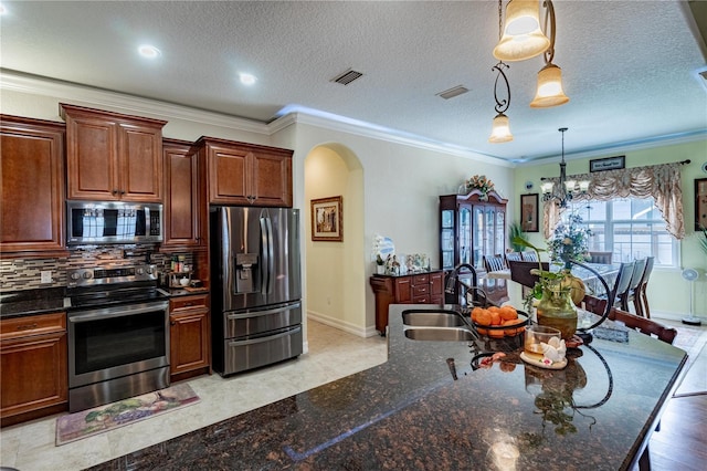 kitchen featuring sink, crown molding, stainless steel appliances, and decorative light fixtures