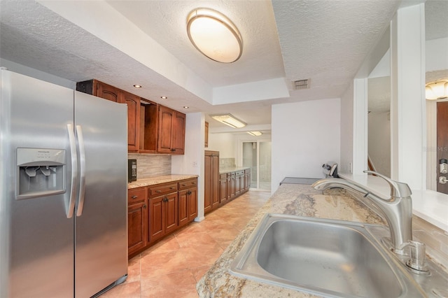 kitchen with tasteful backsplash, light countertops, visible vents, a sink, and stainless steel fridge with ice dispenser