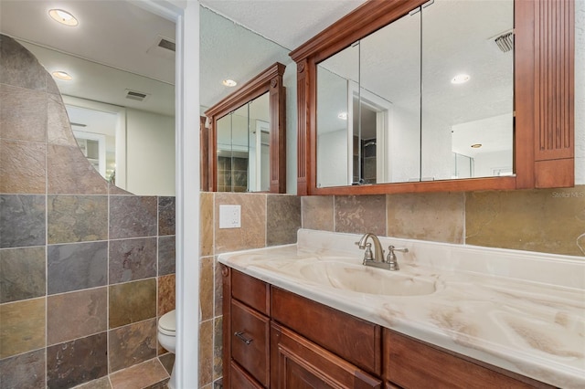 bathroom with visible vents, tile walls, toilet, and vanity