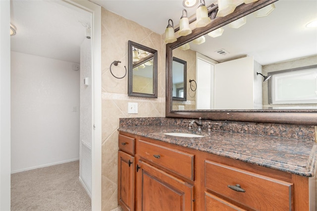 bathroom with baseboards, visible vents, tile walls, and vanity