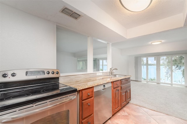 kitchen with light colored carpet, visible vents, appliances with stainless steel finishes, brown cabinetry, and a sink