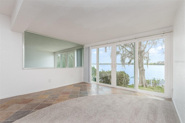 spare room featuring a water view, plenty of natural light, and a textured ceiling