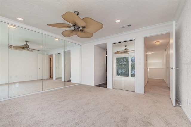 unfurnished bedroom with carpet, visible vents, crown molding, and a textured ceiling