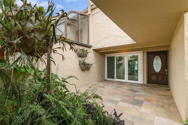 property entrance with a patio and stucco siding