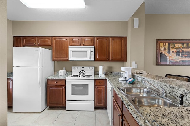 kitchen featuring light stone counters, white appliances, a sink, and light tile patterned floors