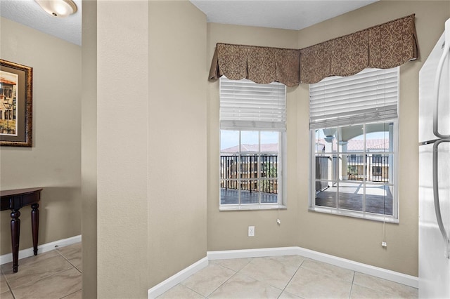 unfurnished room featuring light tile patterned floors and baseboards