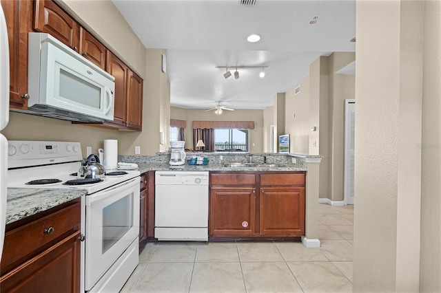 kitchen with light stone counters, light tile patterned floors, a sink, white appliances, and a peninsula