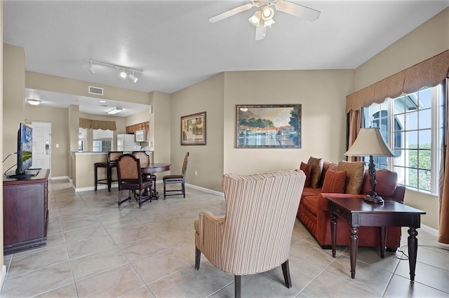 living area featuring ceiling fan, light tile patterned flooring, visible vents, and baseboards