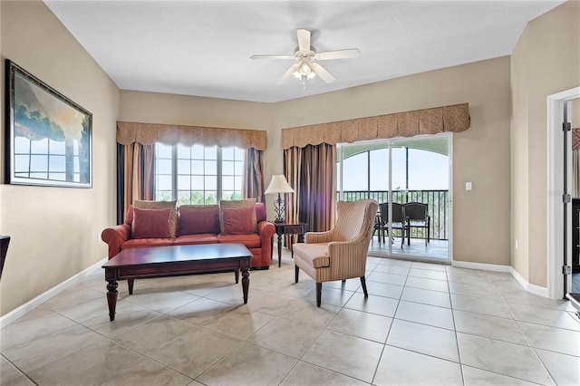 living room featuring light tile patterned floors, ceiling fan, baseboards, and a wealth of natural light