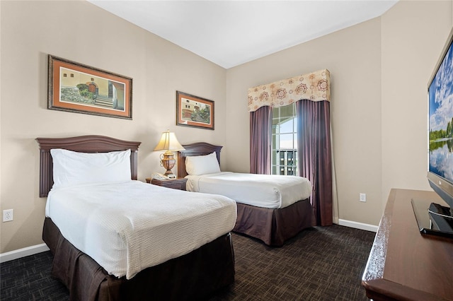 bedroom with dark colored carpet and baseboards