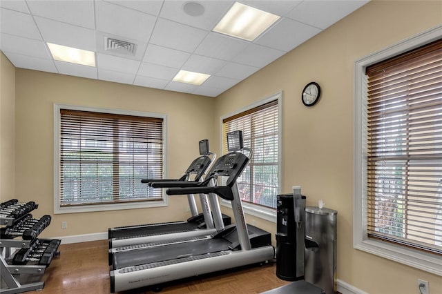 workout room with a paneled ceiling, baseboards, and visible vents