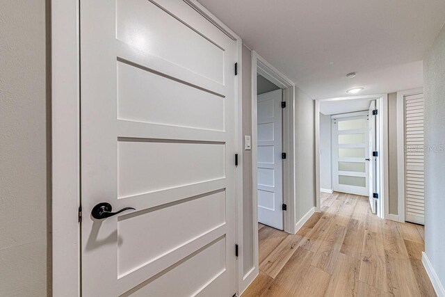 hallway featuring light wood-style floors and baseboards