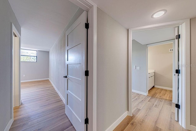 corridor with baseboards and light wood finished floors