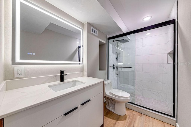full bath featuring toilet, wood finished floors, vanity, visible vents, and a shower stall