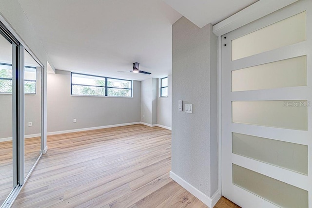 empty room featuring light wood-style floors, baseboards, and a ceiling fan