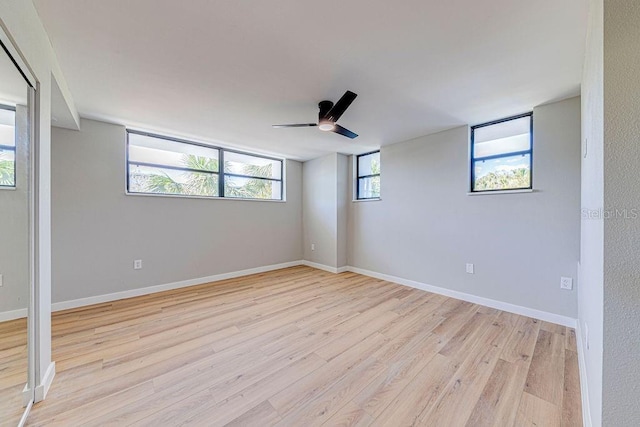 spare room with baseboards, ceiling fan, and light wood finished floors
