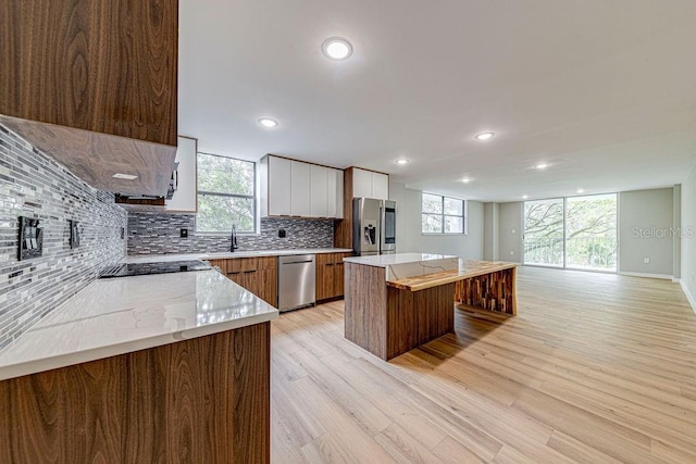 kitchen featuring white cabinets, a kitchen island, appliances with stainless steel finishes, a breakfast bar area, and backsplash