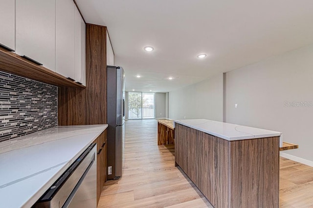 kitchen with tasteful backsplash, white cabinets, light wood-style flooring, modern cabinets, and appliances with stainless steel finishes