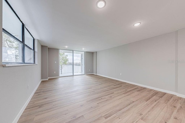 unfurnished room with baseboards, floor to ceiling windows, recessed lighting, and light wood-style floors