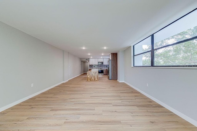 unfurnished living room with baseboards, recessed lighting, and light wood-style floors