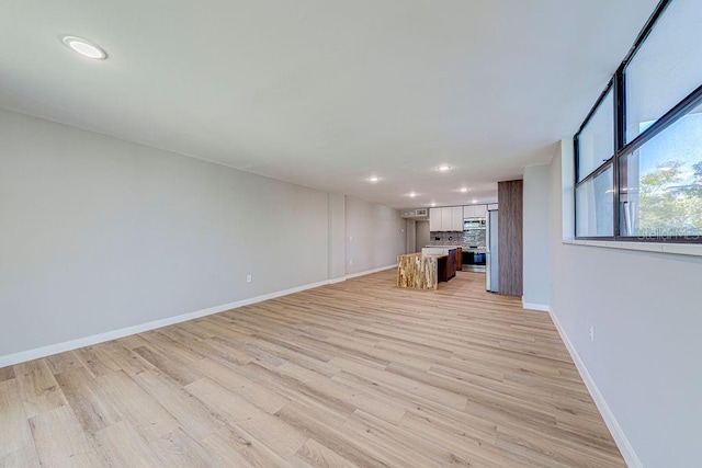 unfurnished living room with light wood finished floors, baseboards, and recessed lighting