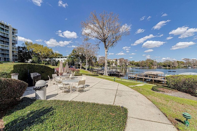 view of property's community featuring a water view, a patio area, and a lawn