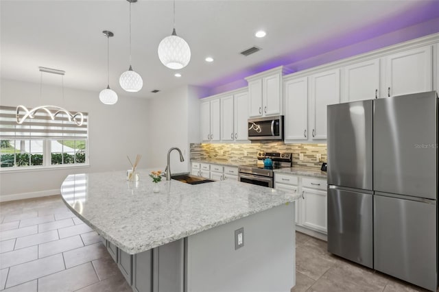 kitchen with an island with sink, appliances with stainless steel finishes, and white cabinetry