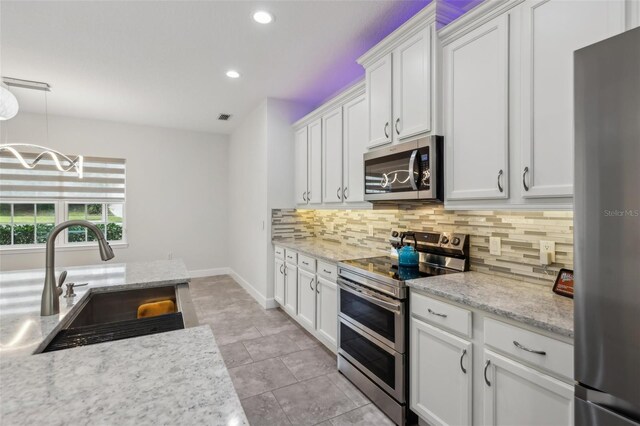 kitchen with appliances with stainless steel finishes, sink, white cabinets, and backsplash