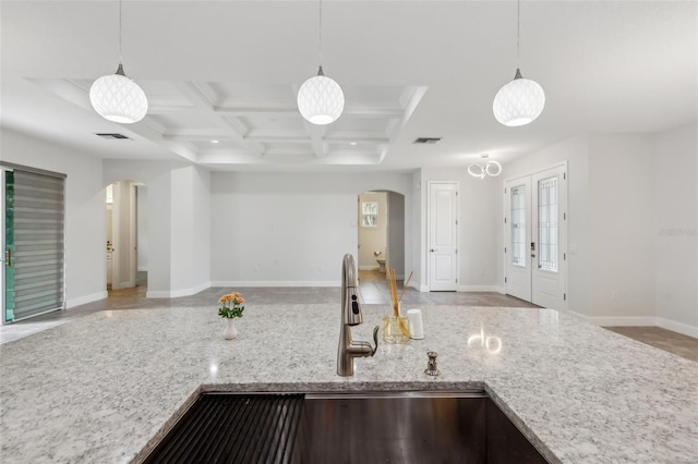 kitchen featuring hanging light fixtures, light stone countertops, coffered ceiling, beamed ceiling, and sink