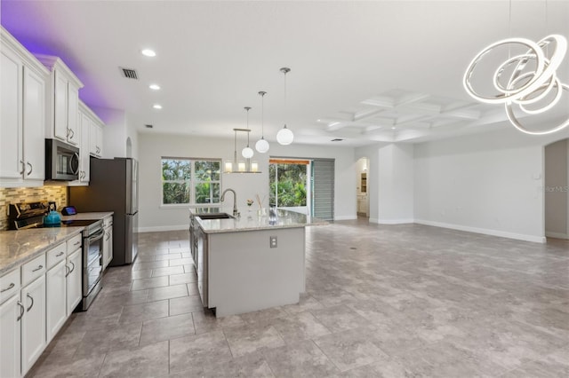 kitchen with appliances with stainless steel finishes, light stone counters, decorative light fixtures, white cabinets, and a kitchen island with sink