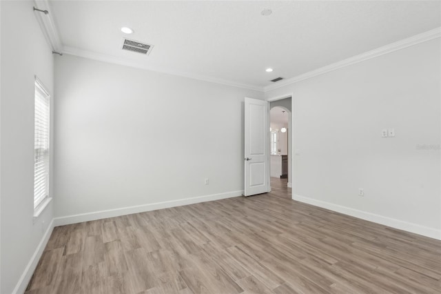 spare room featuring crown molding and light hardwood / wood-style floors