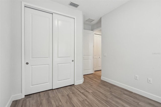 unfurnished bedroom featuring light wood-type flooring and a closet