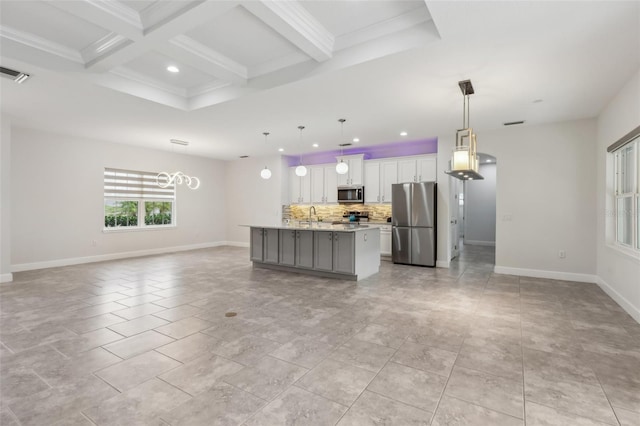 kitchen featuring white cabinetry, a center island with sink, stainless steel appliances, decorative light fixtures, and light stone countertops