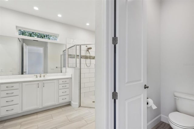 bathroom with toilet, vanity, and a shower with shower door