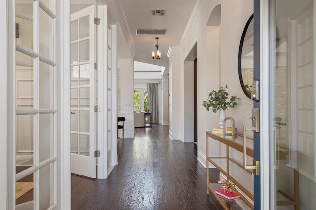 entrance foyer featuring visible vents, baseboards, a notable chandelier, dark wood-style flooring, and crown molding