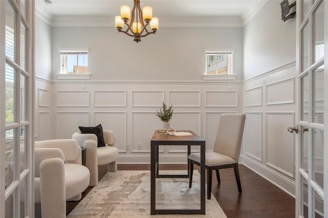 living area with a decorative wall, a notable chandelier, ornamental molding, and wainscoting