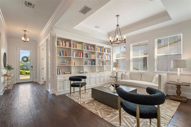 living area featuring visible vents, a chandelier, wood finished floors, and a healthy amount of sunlight