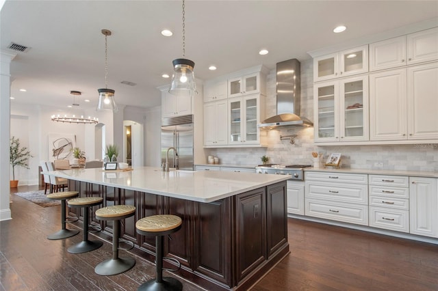 kitchen featuring tasteful backsplash, visible vents, wall chimney exhaust hood, stainless steel appliances, and arched walkways