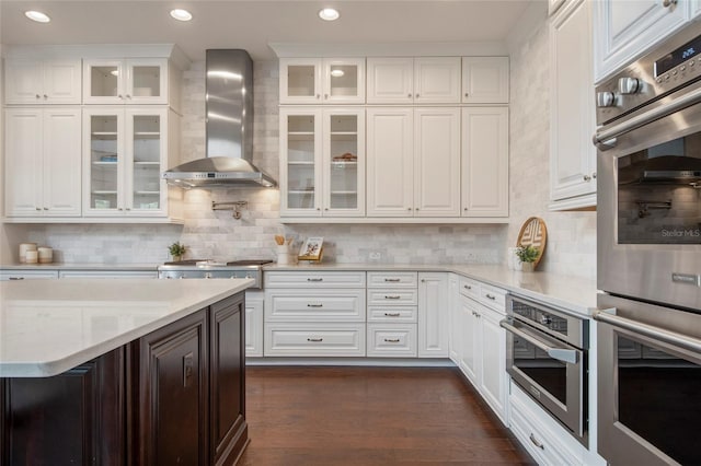 kitchen featuring white cabinetry, wall chimney range hood, appliances with stainless steel finishes, and dark wood finished floors