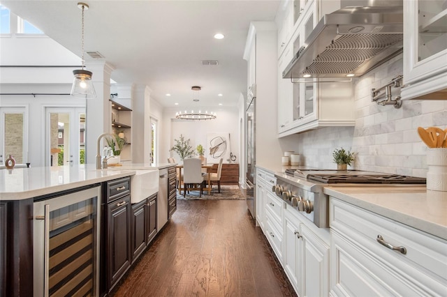 bar featuring exhaust hood, a sink, dark wood finished floors, stainless steel gas cooktop, and beverage cooler
