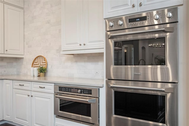 kitchen with decorative backsplash, white cabinets, and double oven