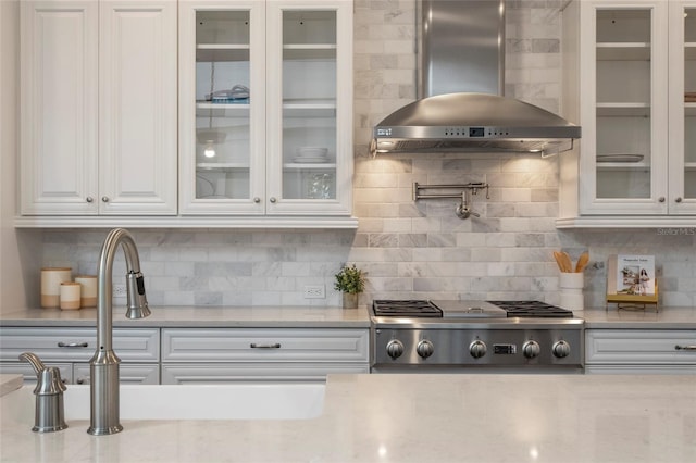 kitchen with decorative backsplash, white cabinetry, stainless steel gas cooktop, and wall chimney exhaust hood