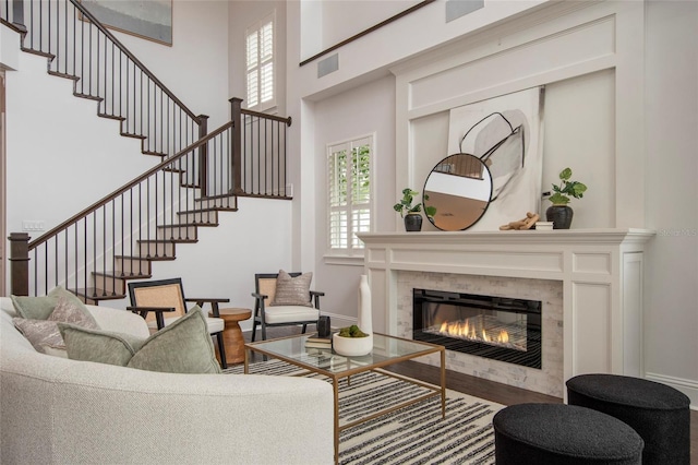 living area with a tiled fireplace, a wealth of natural light, baseboards, and stairway